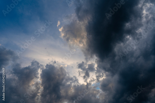 Dark gray clouds fly across the sky. Puffy fluffy grey clouds at spring day during sunset