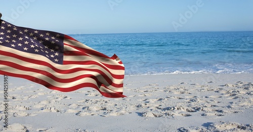 Composite image of waving american flag against beach in background