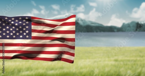 Composite image of waving american flag against landscape with grassland and mountains