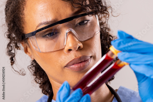 Close-up of african american mid adult female doctor wearing protective eyewear holding test tube