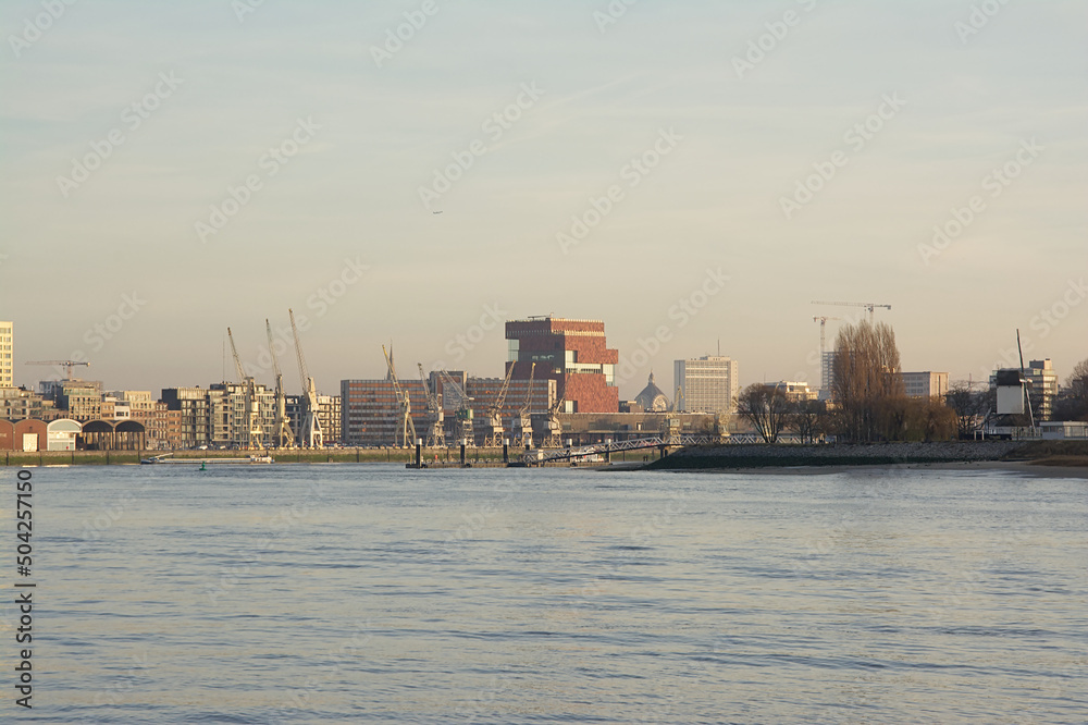 Antwerp skyline from across river Scheldt, with MAS museum, old industrial cranes and new residential skyscrapers in warm evening light

