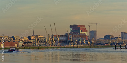  Antwerp skyline from across river Scheldt in wam evening light, featuring the MAS museum with it`s collection of old industrial cranes and new apartment buildings  photo