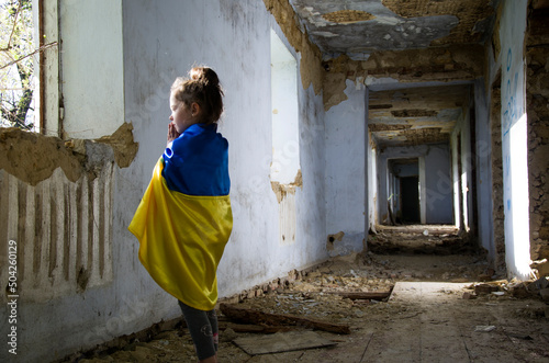 The girl prays for peace. War in Ukraine. A child in a war-torn house. Rocket attacks on Ukrainian cities. A child in a bomb shelter. Peace concept. Destroyed Ukrainian houses