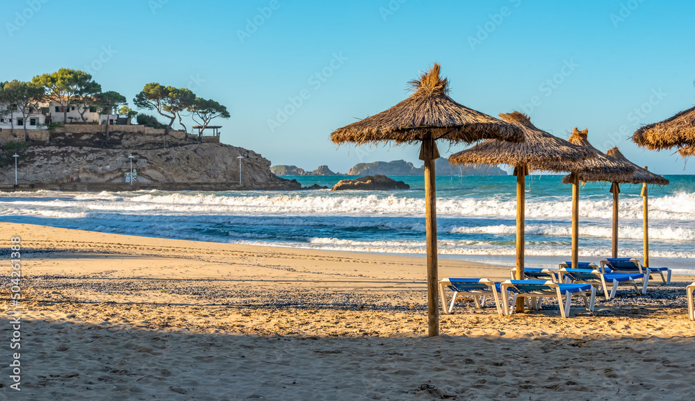 deserted morning sea beach with sunny screens. Platja Palmira