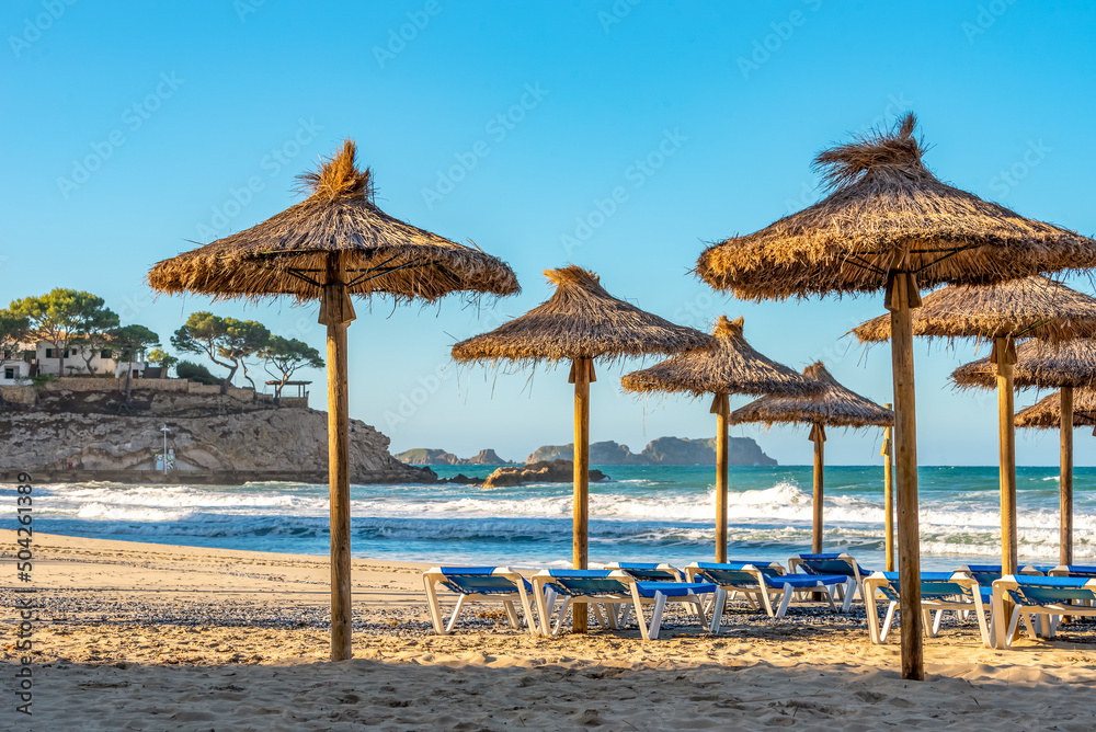deserted morning sea beach with sunny screens. Platja Palmira