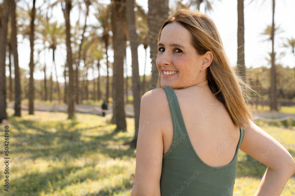 Happy young woman in green dress walking in a park outdoors. Happy young woman in green dress walking in a park outdoors.