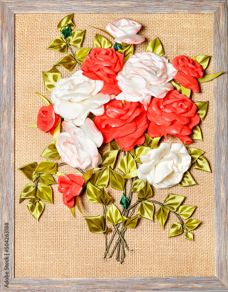 Artificial flowers of red and white roses in a frame, like a 3D painting.