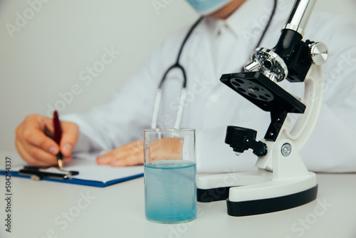 Scientist or medical in lab coat working in biotechnological laboratory. Microscope equipment for research and flask