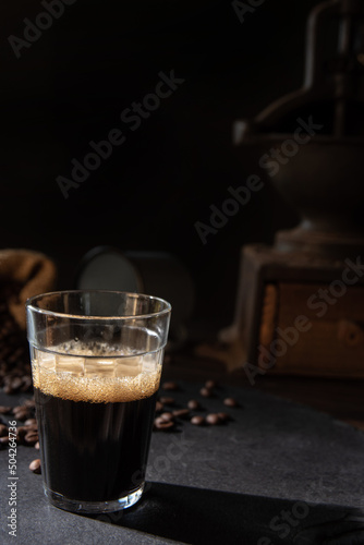 Coffee, cup with coffee and coffee beans on a gray stone over wood, dark food style photo, selective focus.