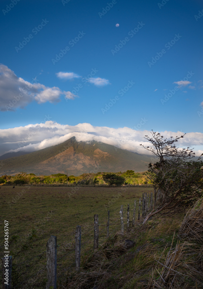 Farm landscape with volcano and clouds