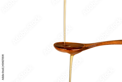 A jet of sunflower oil into a wooden spoon and from a spoon on a white background.