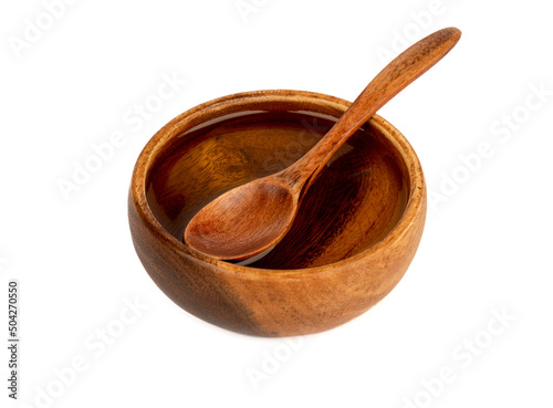 Wooden bowl with sunflower oil and a spoon on the surface of the oil.
