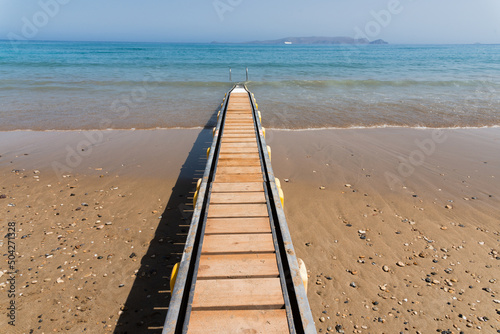 Fototapeta Naklejka Na Ścianę i Meble -  Safe motorized wheelchair ramp, used to transport disabled people into the sea water for swimming. Heraklion, Crete, Greece