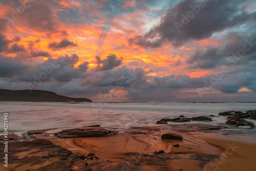 Soft sunrise seascape with rocks and rain clouds