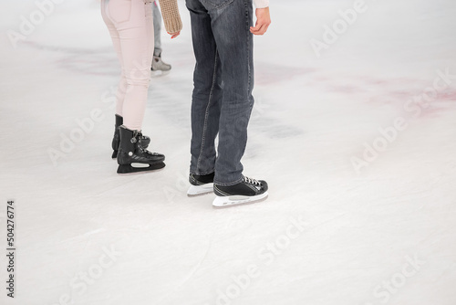 Legs of a man and woman skating on an ice rink. Winter holidays leisure