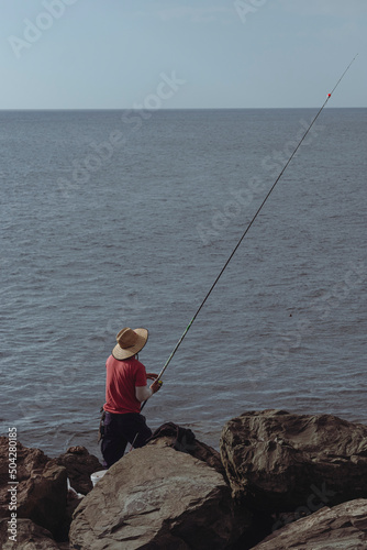 Man fishing on the seashore from the rocks.