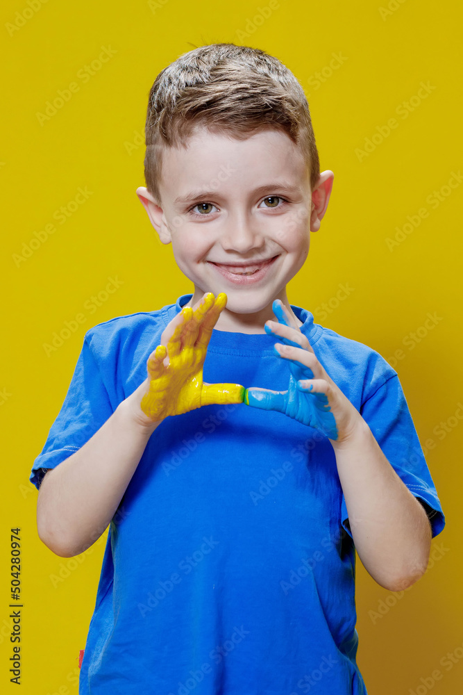 Little happy boy with painted palms in yellow and blue, the colors of the flag of Ukraine. Ukrainian creative preschooler Little happy boy with painted palms in yellow and blue, the colors of the flag of Ukraine. Ukrainian creative preschooler