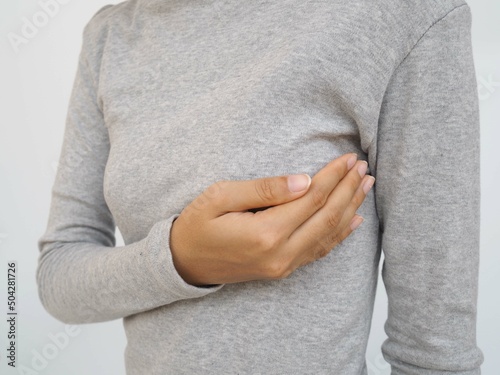 Young woman examining her breast for lumps or signs of breast cancer on white background. closeup photo, blurred. photo