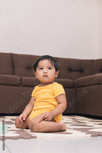 baby kneeling in the living room of the house watching photo