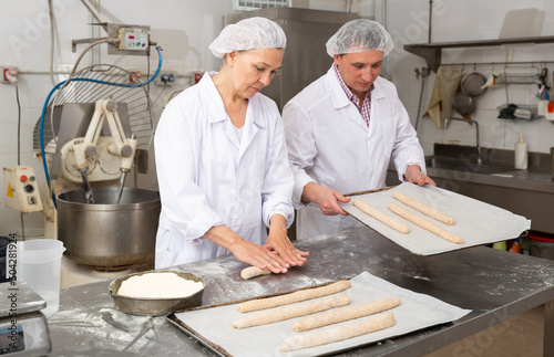 Bakery worker preparing raw baguette dough for baking. High quality photo