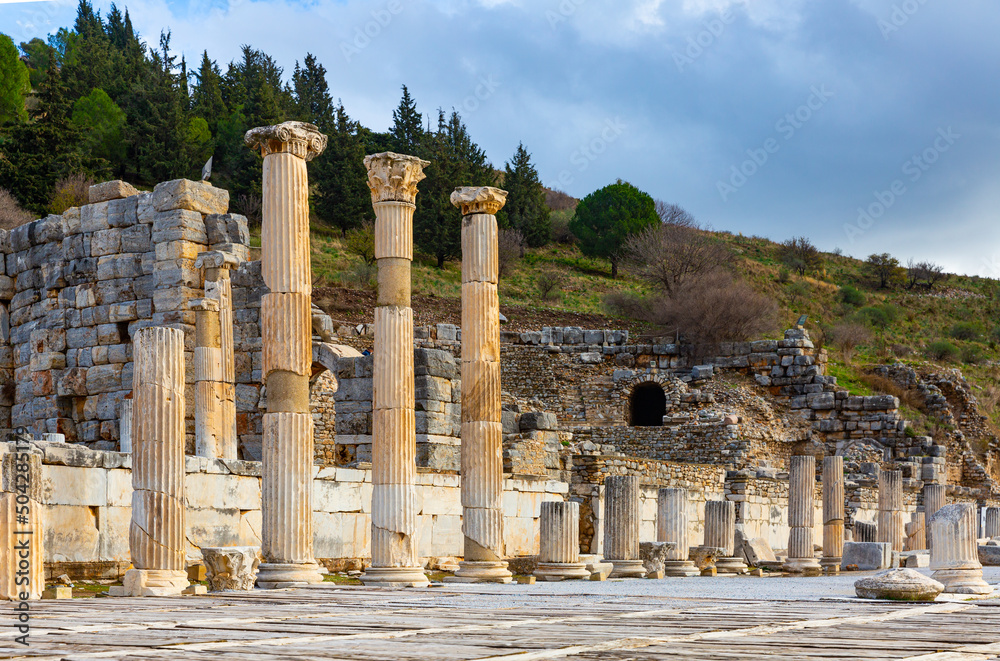 Remaining elements of State Agora columns with Corinthian capitals in ancient Greek city of Ephesus with Odeon ruins in background, Selcuk, Turkey