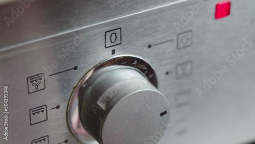 Metallic Toggle Switch of the Cooker Oven Close-up. Front panel of modern oven. Switching on the stove, baking oven and changing modes in order to preheat and cook meal. High quality 4k footage photo