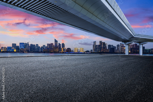 Empty asphalt road and modern city skyline with buildings in Hangzhou at sunset, China.