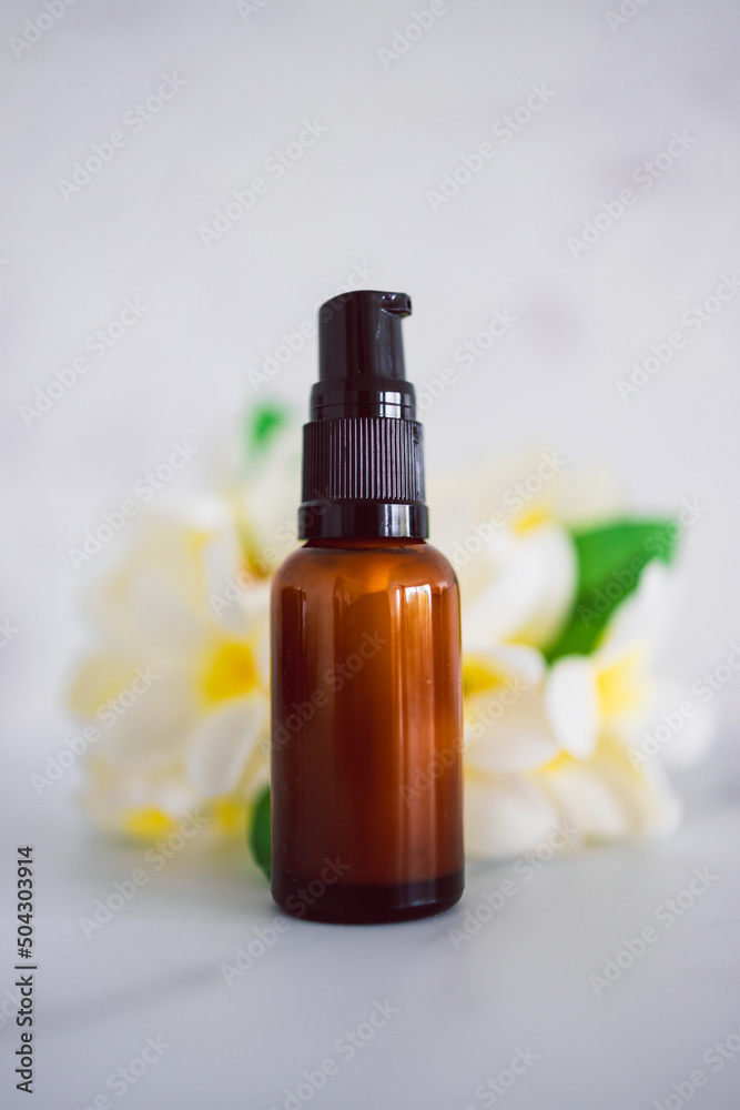 natural beauty and organic ingredients in skincare, apothecary skincare bottle with tropical flowers bokeh