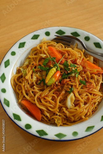 a plate of noodles cooked in sauce with vegetables 