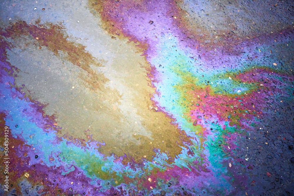 Oil stain on the asphalt, rainbow-shaped colored gasoline stains on an asphalt road as a texture or background