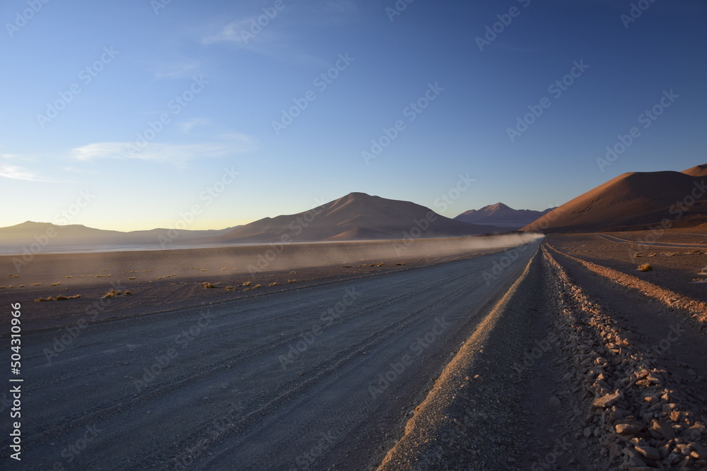 Sandy road through the desert at sunrise in Eduardo Avaroa National Reserve in Uyuni, Bolivia.