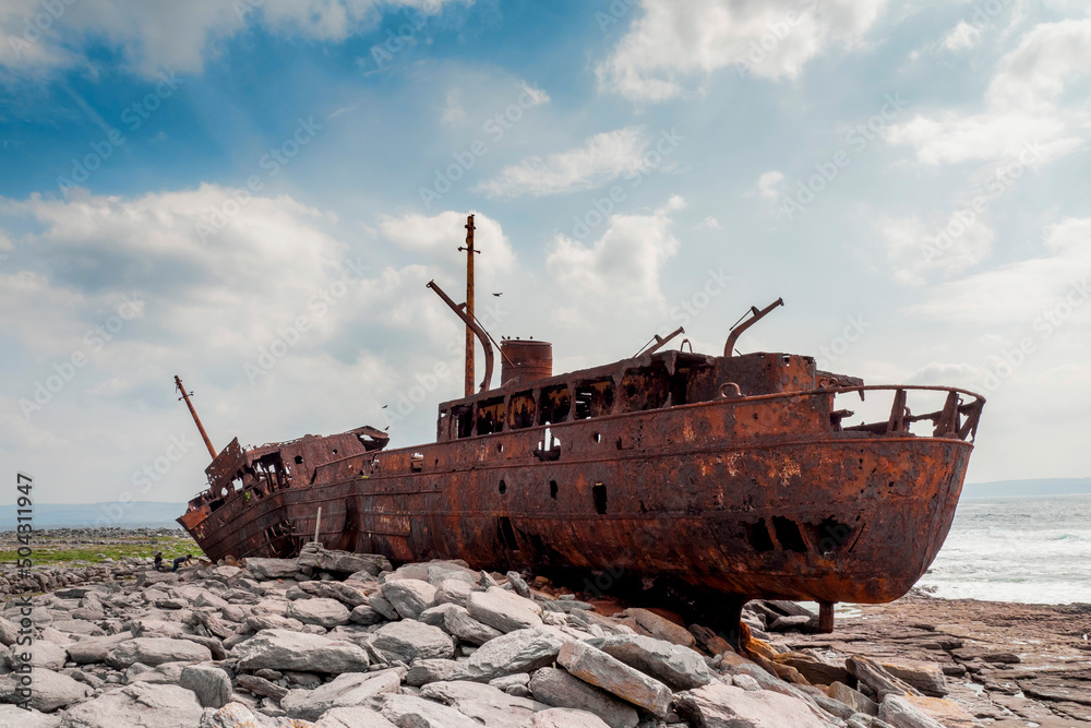 Plassey shipwreck on shore of Inisheer island. Aran islands, county Galway, Ireland. Rough stone coast and blue cloudy sky. Popular tourist landmark and attraction. Irish landscape