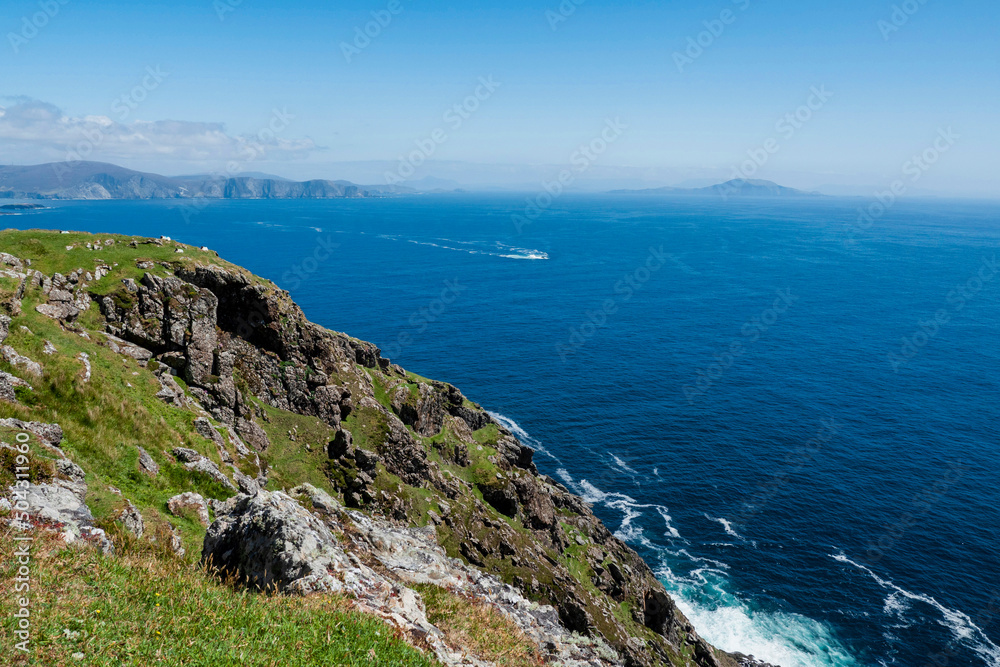 Stunning nature scene of Achill island, county Mayo, Ireland. Green hills and blue sky and ocean surface. Irish landscape. Warm sunny day. Popular travel area.