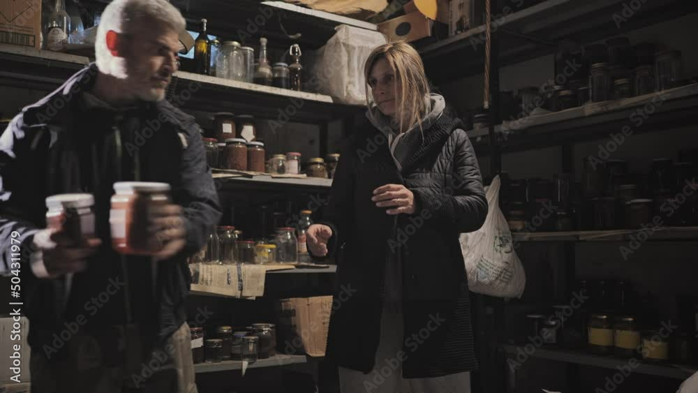 War,caucasian family storing food supplies in the basement shelter,man and woman concerned of the coming war stockpiling food reserves in the bunker