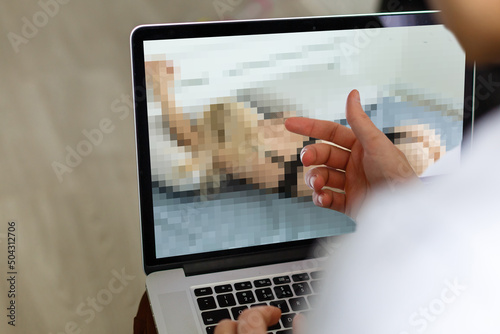 closeup of a young caucasian man watching a nude woman in his computer photo