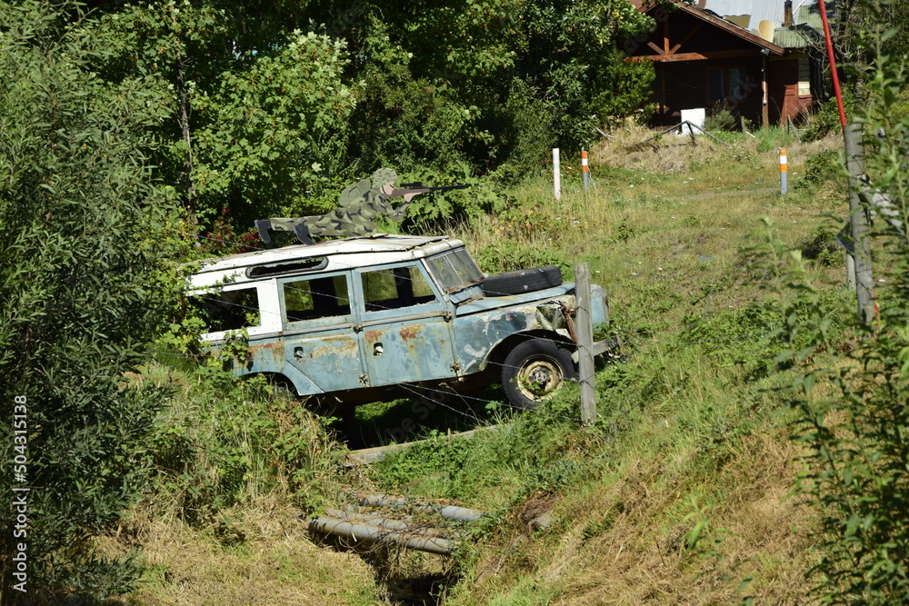 A rusty jeep behind barbed wire in a ditch, in a small cozy town of Pucon. Chile