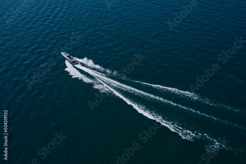 Boat performance movement on the water aerial view. High-speed luxury boat driving on dark blue water. © Berg
