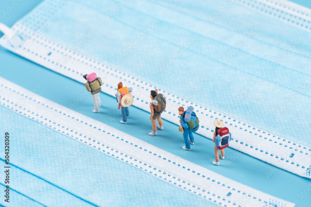 Obraz premium Miniature people travel with face mask on blue background,safety travels