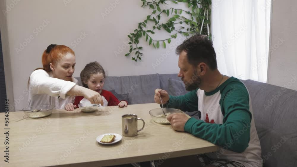 The family eats hot oatmeal porridge for breakfast in the kitchen, the girl has chickenpox The family eats hot oatmeal porridge for breakfast in the kitchen, the girl has chickenpox