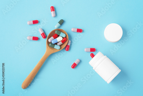 Pills on wooden spoon with white medicine bottle