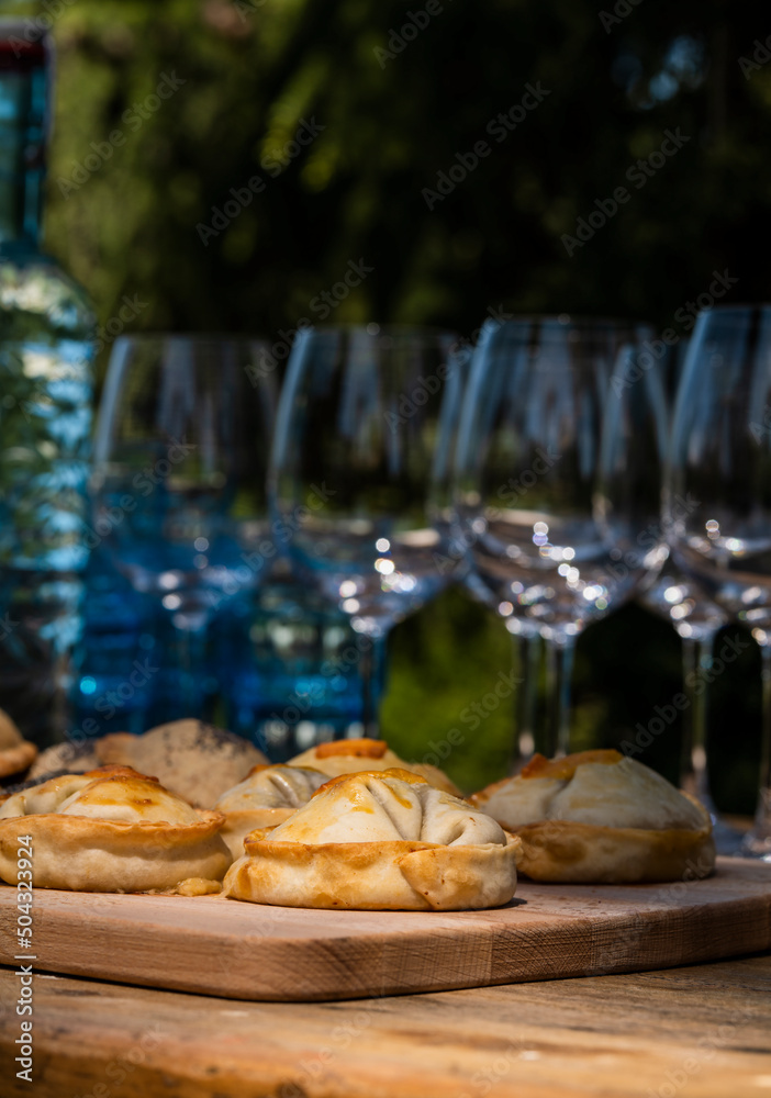 Argentinian stuffed pastries on table with glass bottles and cups