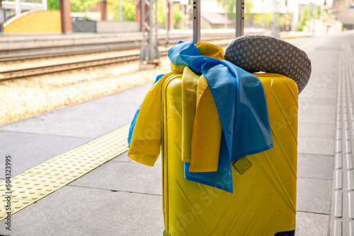 yellow valise with ukrainian flag at railway station