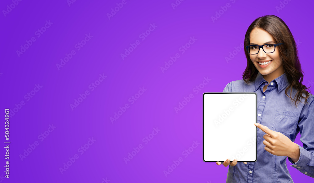Happy smiling businesswoman in eye glasses spectacles showing touchpad tablet pc, with white screen copy space text area for advertising or slogan sign, isolated on purple background. Business woman. Happy smiling businesswoman in eye glasses spectacles showing touchpad tablet pc, with white screen copy space text area for advertising or slogan sign, isolated on purple background. Business woman.