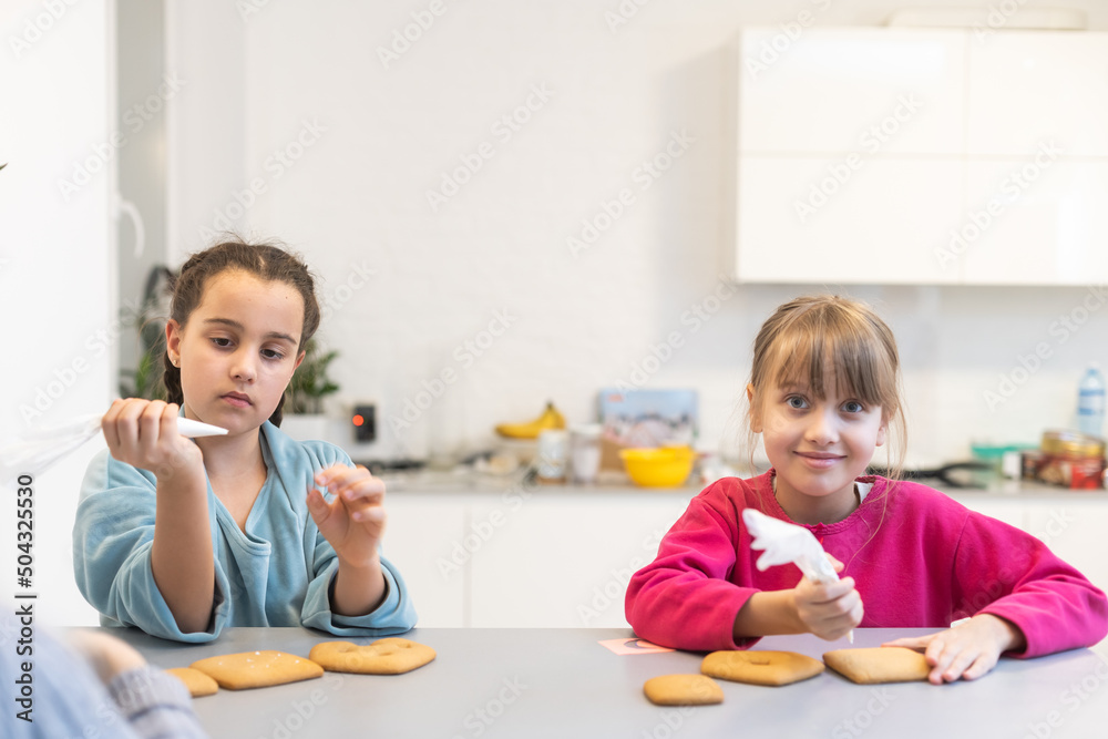 two cute sisters make and decorate cookies