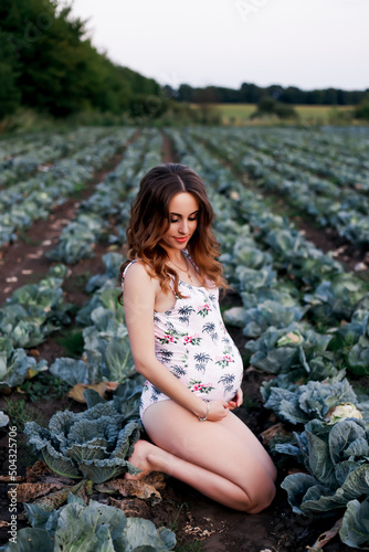 Vinnytsia, Ukraine. July 26, 2022. A young Ukrainian beautiful girl is sitting in a cabbage and waiting for a baby