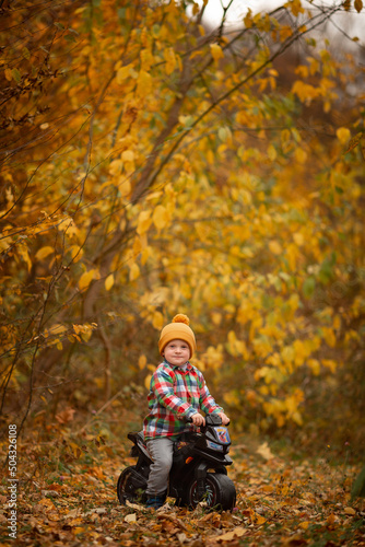 Vinnytsia, Ukraine. October 26, 2021. A little boy on his autumn motorcycle in a yellow leaf. Selective focus