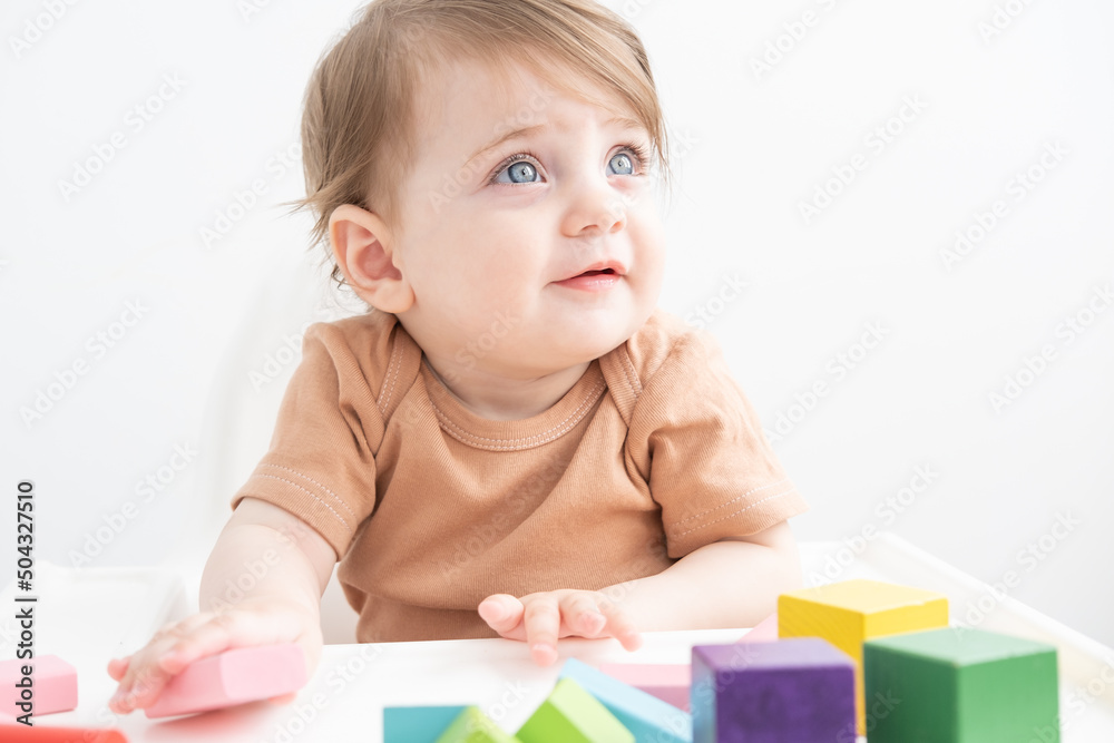 cute baby girl playing with colorful wooden blocks at child chair. early children development cute baby girl playing with colorful wooden blocks at child chair. early children development
