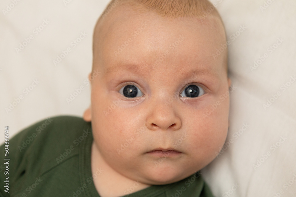 close-up portrait of a three-month-old baby with blue eyes dressed in green