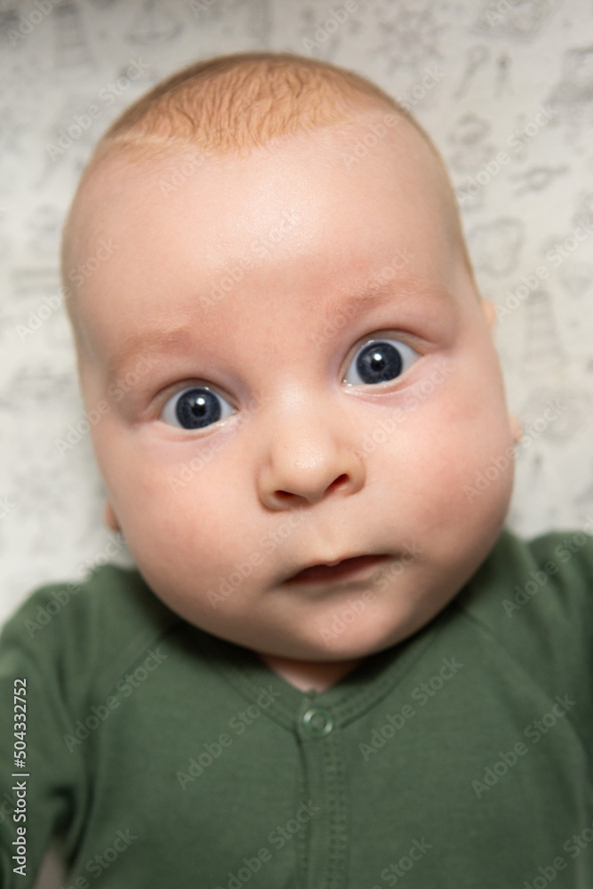 close-up portrait of a three-month-old baby with blue eyes dressed in green close-up portrait of a three-month-old baby with blue eyes dressed in green