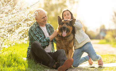 Grandfather and granddaughter with dog shepherd in the garden